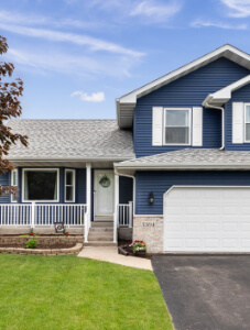 Exterior of a suburban home with blue siding, a white front porch, and white shutters.